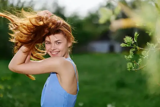 Женщина с красивой улыбкой, обнажающей зубы, весной в солнечный день, счастливая на природе на фоне зеленой травы, концепция здоровья женского тела без аллергии