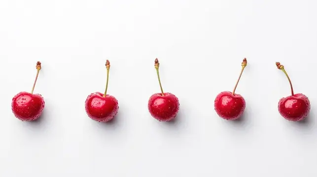 Пять спелых вишен с каплями воды в ряд на белом фоне