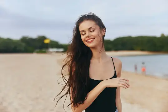 Женщина в джинсах бежит по пляжу на закате