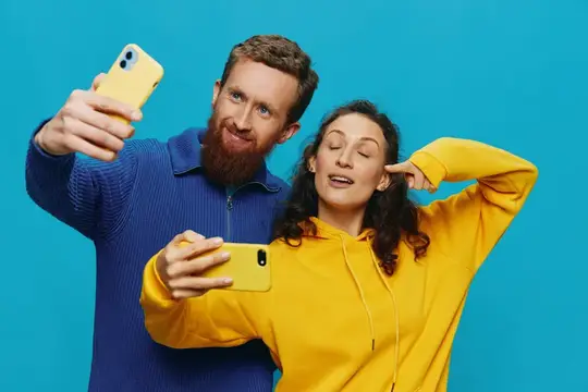 Бородатый мужчина и женщина делают селфи на жёлтые смартфоны
