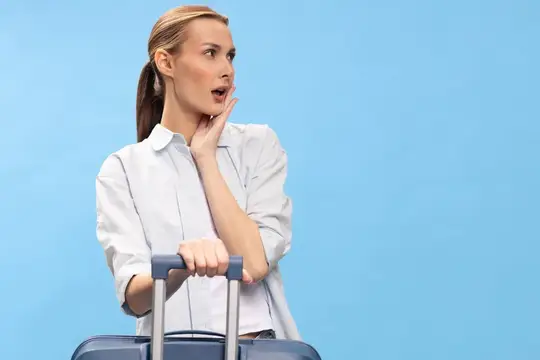 Удивленная светловолосая женщина с чемоданом на голубом фоне