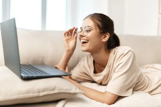 Улыбающаяся женщина работает за ноутбуком в уютном домашнем офисе