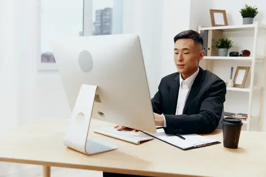 Азиатский бизнесмен в костюме работает за компьютером в офисе
