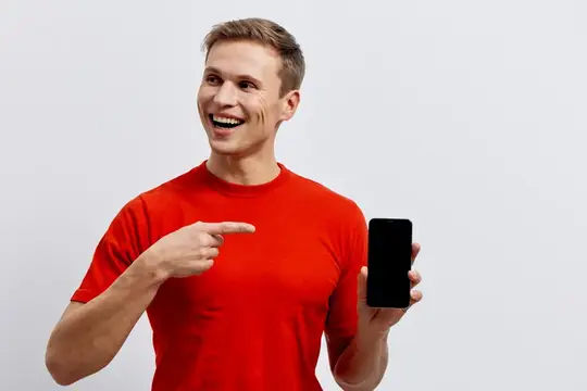 Улыбающийся парень в красной футболке указывает на смартфон