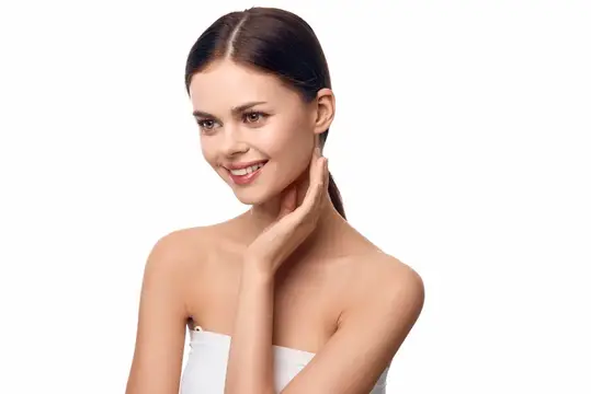 Улыбающаяся темноволосая девушка с ухоженной кожей на белом фоне