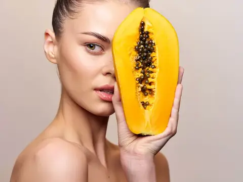 Красивая молодая женщина с маской для лица из папайи