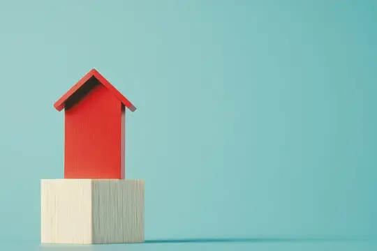 Красный деревянный домик стоит на белом кубике на голубом фоне