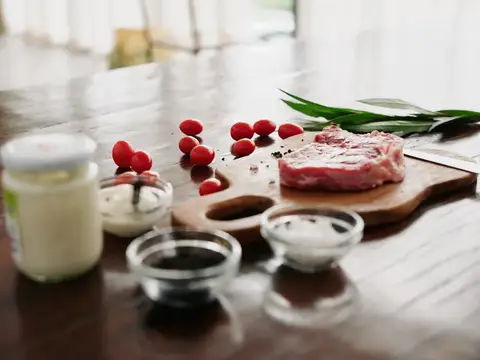 Сырое мясо с розмарином и специями на деревянной доске