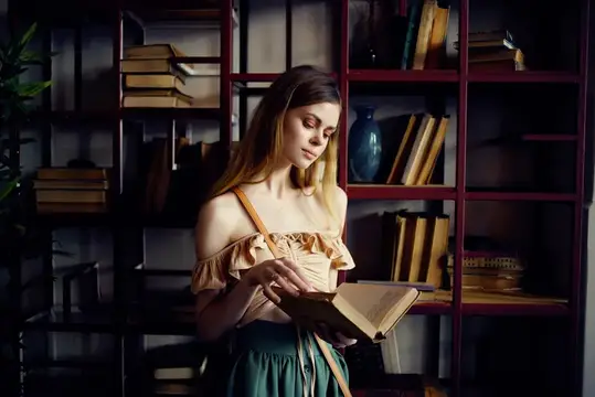 Весёлая женщина читает книгу, отдыхая в кафе