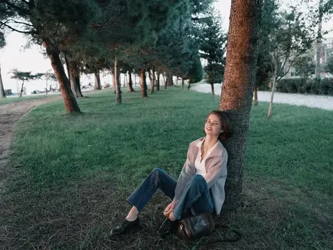 Молодая женщина отдыхает под сосной в парке