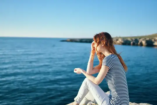 Женщина на скале у моря в горах, закат, лето