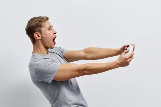 Удивлённый парень в серой футболке играет в видеоигру