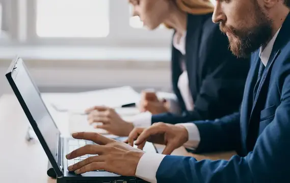 Мужчина и женщина в офисных костюмах работают за ноутбуками