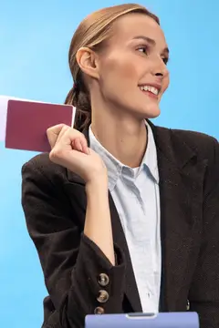 Улыбающаяся светловолосая женщина в деловом костюме держит паспорт