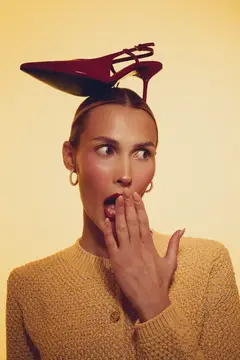 Удивлённая женщина с красной туфлей на голове