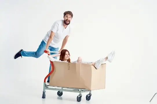 Мужчина везёт женщину в коробке на тележке