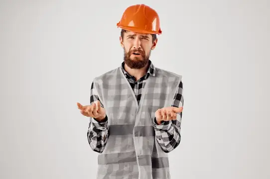 Инженер в оранжевой каске рассматривает чертежи в профессиональной студии