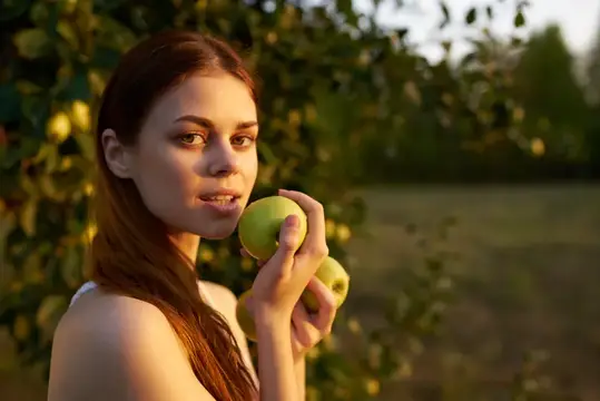 Счастливая женщина с яблоками в руках на природе