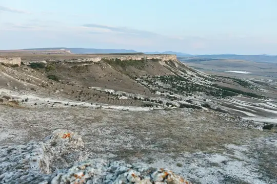 Скалистый обрыв и поросшие лесом склоны долины в сумерках