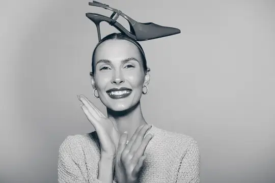 Улыбающаяся женщина с туфлей на голове в чёрно-белом кадре