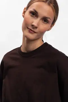 Молодая женщина с гладко зачесанными волосами в коричневой футболке
