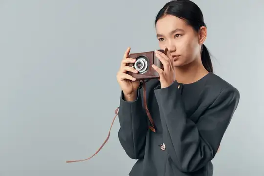 Молодая женщина делает снимок с помощью классического винтажного фотоаппарата