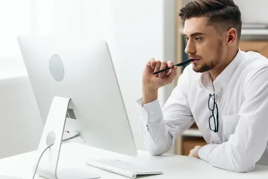 Менеджер в белой рубашке сидит за компьютером, работая с документацией
