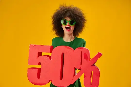Кудрявая женщина в зелёных очках держит красные цифры 50%