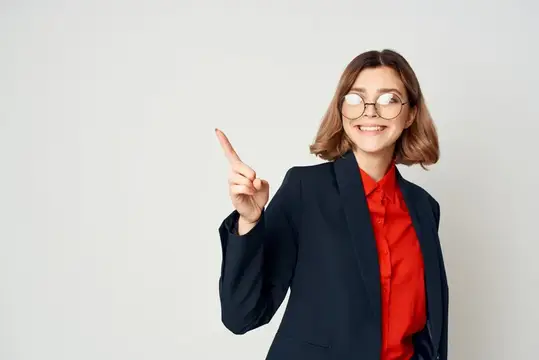 Улыбчивая девушка в очках и красной рубашке указывает пальцем вверх