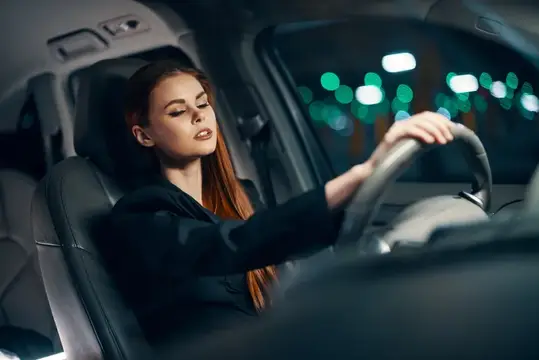 Рыжеволосая девушка за рулём автомобиля ночью