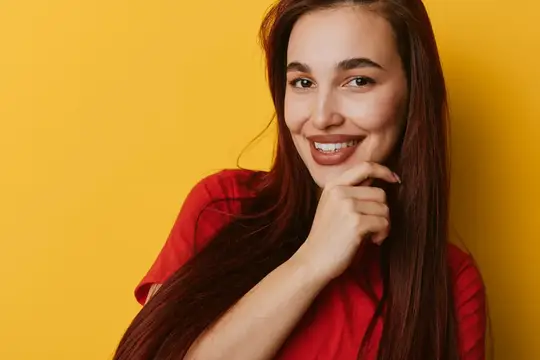 Улыбающаяся темноволосая девушка в красной футболке на жёлтом фоне