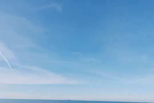 Ясное голубое небо с тонкими перистыми облаками над морем