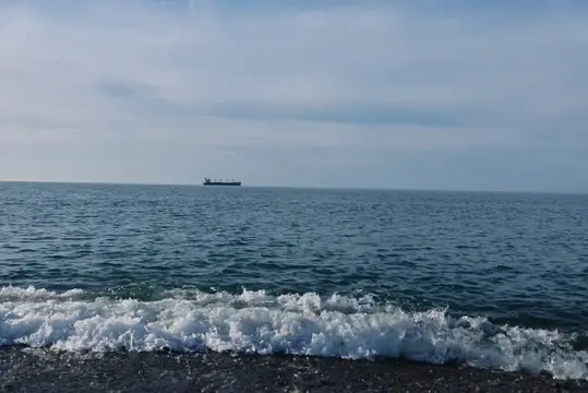Одинокий грузовой корабль на горизонте спокойного моря