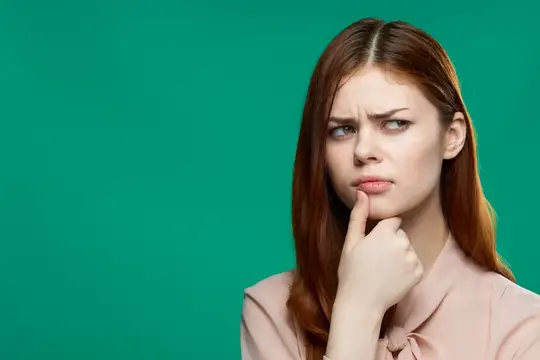Красивая женщина демонстрирует эмоции, держа руку возле лица на фоне косметической студии с зелёным фоном