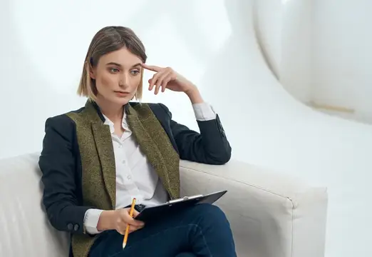 Деловая женщина сидит в кресле, работая в офисе с профессиональными документами