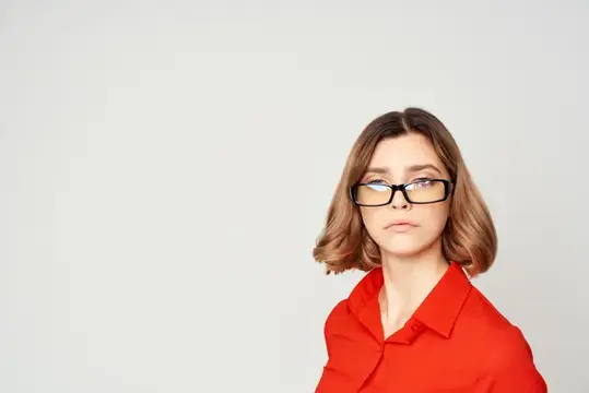Молодая женщина в очках и красной рубашке на светлом фоне