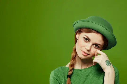 Счастливая женщина в зелёной футболке и шляпе с трилистником празднует День Святого Патрика