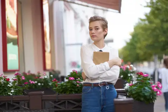 Молодая женщина с планшетом стоит у кафе с цветами