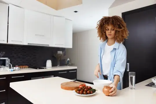 Кудрявая девушка готовит ужин на светлой кухне