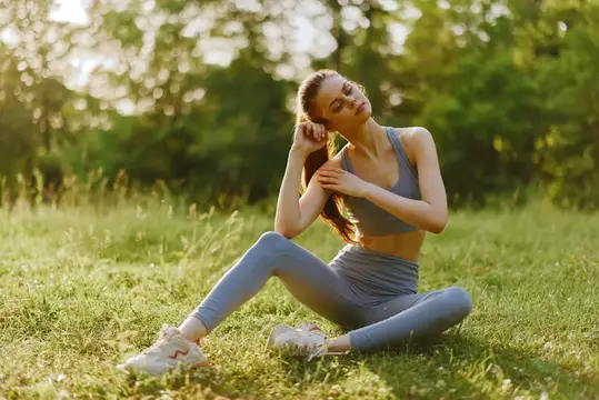 Молодая женщина в спортивной форме отдыхает на траве в парке
