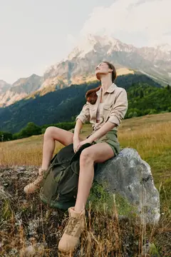 Девушка с рюкзаком отдыхает на камне в горах