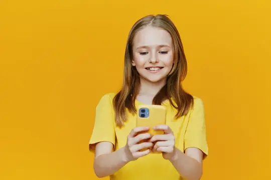 Улыбающаяся девочка со смартфоном на жёлтом фоне