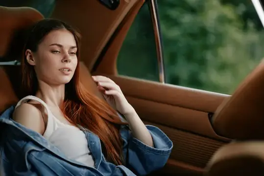 Молодая рыжеволосая женщина отдыхает в салоне автомобиля