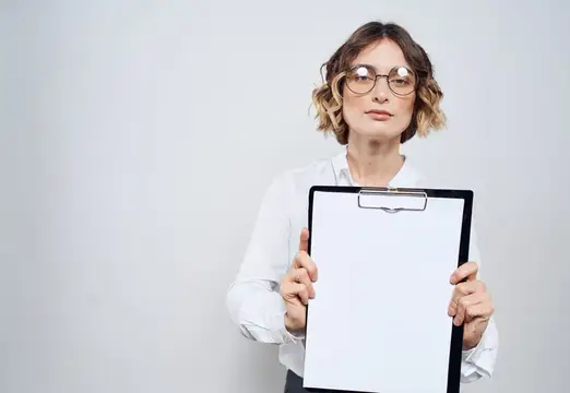 Женщина с белым листом бумаги, папкой и документами на сером фоне