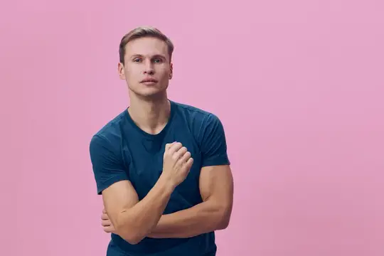 Молодой блондин в синей футболке на розовом фоне