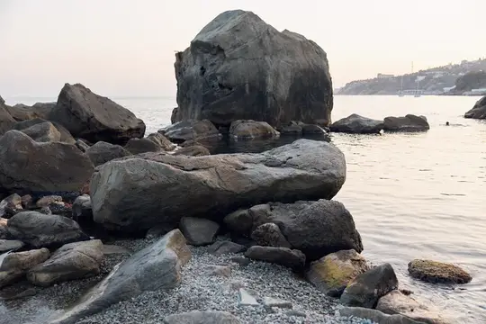 Большие серые камни на галечном берегу у спокойного моря