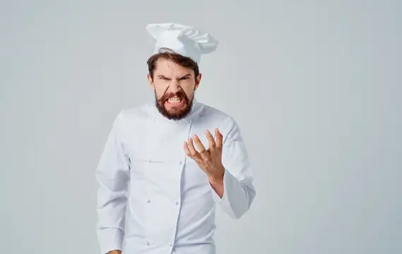 Разъяренный бородатый повар в белом колпаке на сером фоне