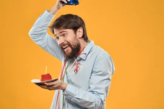 Бородатый мужчина льёт воду из бутылки на торт с свечой