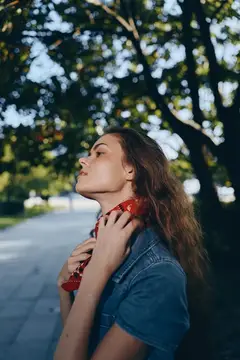 Молодая женщина с красным платком на шее в парке