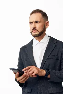 Серьёзный мужчина в костюме смотрит в смартфон на белом фоне